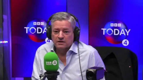 Ted Sarandos in the BBC radio studio with headphones, a mic, wearing a blue shirt
