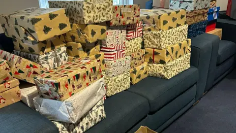 ARC A photo showing a pile of wrapped Christmas presented stacked up on two chairs
