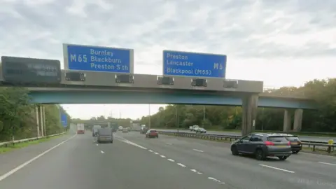 Googleview showing vehicles on the motorway with blue motorway signs overhead indicating the M65 route to Bunrley, Blackburn and Preston South and the M6 route to Lancaster and Blackpool