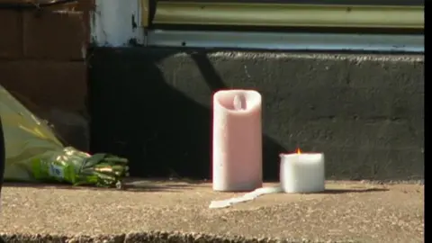 Two candles, one pink and white, sitting outside a house 