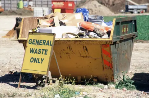 A skip is seen filled with rubbish