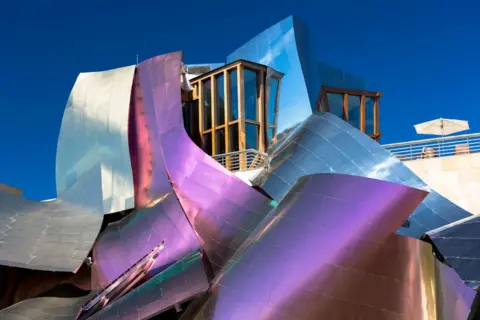 Tim Graham/Getty Images Hotel Marques de Riscal Bodega in Spain with its iconic purple cladding glistening in the sun. The facade is a chaotic combination that laces around itself with a sundeck on top.