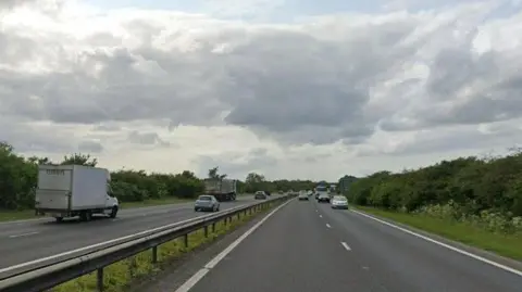 View of part of the A14. It is a dual carriageway road and cars and lorries are driving along both sides.
