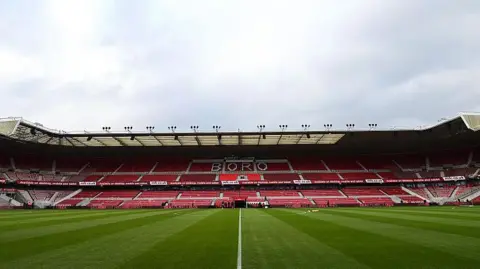 A view of the main stand at Middlesbrough's Riverside Stadium with "Boro" in white letters across the seats in the upper tier 