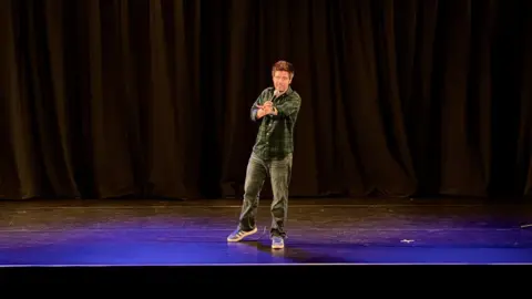 Your Trust Rochdale Photograph of the comedian Ed Patrick on stage on the opening night at Heywood Civic. The image was taken by Your Trust Rochdale..