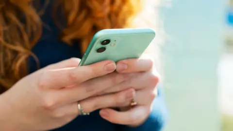 Getty Images Woman holding turquoise iPhone in both hands with finger touching the screen