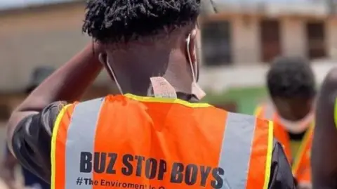 Buz Stop Boyz Back view of a man wearing an orange Buz Stop Boys vest