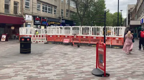 Pete Cooper/BBC Abington Street in Northampton with new paving in the foreground and restrictive fencing through the centre as work continues.