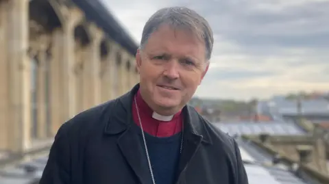 Jenny Kirk/BBC The Bishop of Norwich, the Right Reverend Graham Usher standing on the roof of St Peter Mancroft church