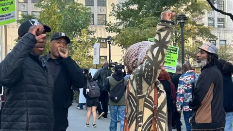 Un gruppo di manifestanti, alcuni dei quali alzano i pugni in aria, si raduna davanti a un tribunale di New York City