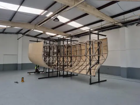 Aivaf A replica ship under construction. The stainless steel frame is clearly visible, being clad in a light brown outer skin