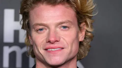 Getty Images Tom Rhys Harries who has blonde hair smiles at the camera