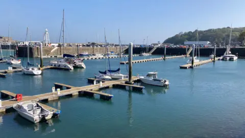 A marina with several pontoons with just a few boats moored up alongside