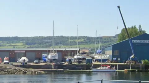 A marina, with several sailing boats visible around it.