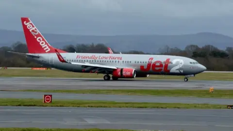 A Jet2 plane is landing on the tarmac at Manchester airport.