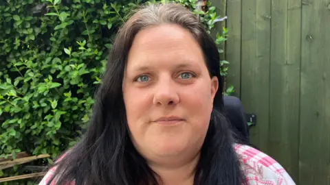 SteveJones/BBC Caroline Gibson, who has dark hair and blue eyes. She is smiling at the camera.