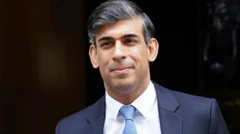 PA Media Rishi Sunak wearing a suit and blue tie is seen leaving 10 Downing Street during his final days as prime minister.