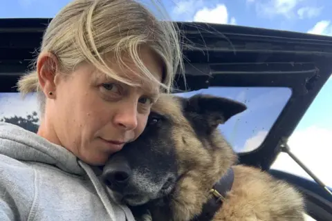 Claire Harrison PC Claire Harrison cuddling a Polly, a large German shepherd-Belgian malinois cross dog.