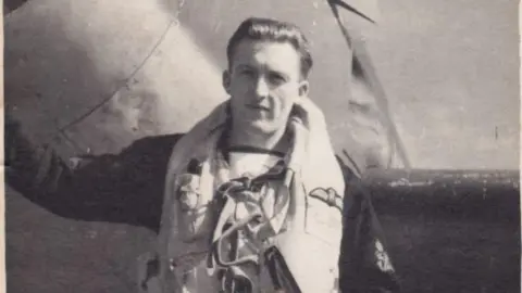 Rose Mary Murphy An old black and white photo of Petty Officer Smith in navy uniform standing beside a plane. 