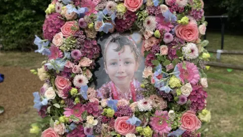 A photo of Sofia Le Brunn-Healey in a large floral frame. It is displayed outdoors.