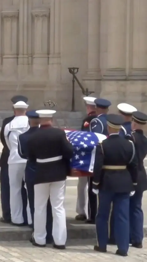 Service members hold a casket draped in the US flag into the National Cathedral, Washington DC.