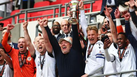 Andy Woodman lifts the National League promotion final trophy with Bromley players