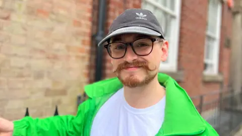 Jonny Cosmo smiling at the camera outside the house