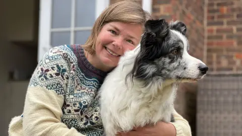 Harvey the border collie is being hugged by his owner Irene Hewlett outside their house in Reading. 