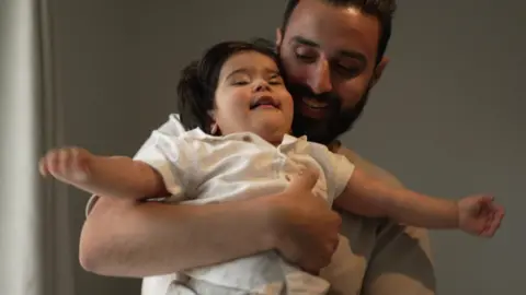 Hasnain playing with Eliyas. Both of them are smiling in the still image.