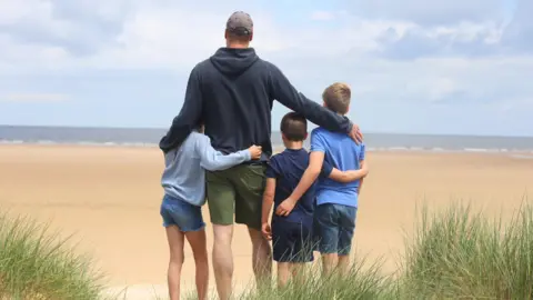 @KensingtonRoyal William and children on a beach looking out to sea