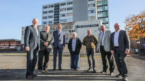 Members of the Thornaby Town Deal Board stand in front of the Golden Eagle. From left, they are Andy McDonald, MP for Middlesbrough and Thornaby East, Steve Walmsley, Mark White CBE DL, Councillor Sylvia Walmsley, Councillor Ray Godwin, Councillor Ian Dalgarno and Councillor Nigel Cooke. Much of the Golden Eagle building is boarded up.