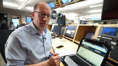 Tom Bateman is pictured in the news desk.