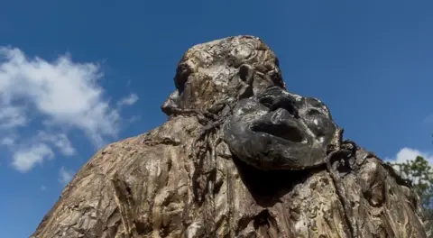 Jamie Niblock/BBC Detail on the shoulder and back of the bronze statue, with a drama mask depicting tragedy in view