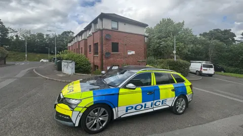 A police car parked outside an apartment block. 