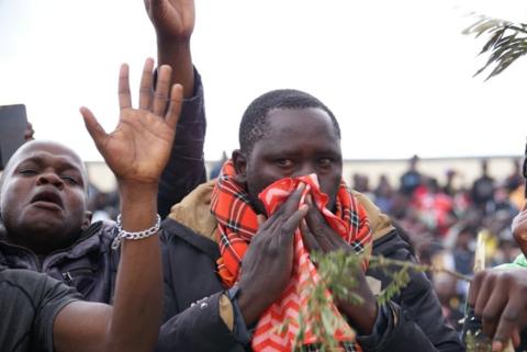 A man crying and mourning, wiping his nose with a red scarf.