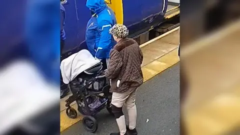 CLEVELAND POLICE CCTV image of person wearing blue coat and person wearing brown coat on train platform