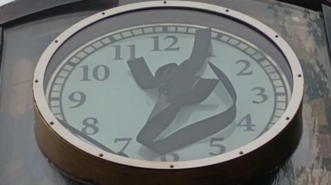 Image of a clock. The hands of the clock are twisted and pointing in different directions