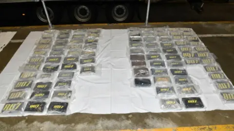 NCA A large quantity of cocaine wrapped in plastic and laid out on a white sheet.