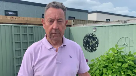 bbc Picture of Steve McGranaghan in the garden with the new building behind him
