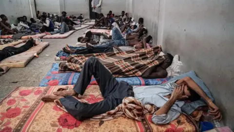 Os imigrantes ilegais de imagens Getty são vistos dormindo em um centro de detenção em Zawiyah, 45 quilômetros a oeste da capital da Líbia Trípoli, em 17 de junho de 2017.
