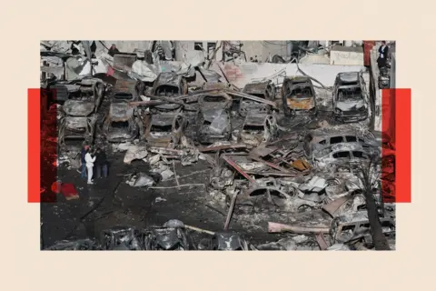 EPA/Shutterstock People walk among the debris of cars and a building destroyed in an Israeili airstrike in the Corniche el-Mazraa neighborhood of Beirut