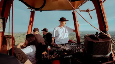 Plaster Communications People in a hot air balloon over Bristol with music equipment visible