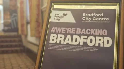 Aisha Iqbal/BBC A framed certificate supporting Bradford's "purple flag" status 