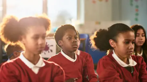 School children in red uniform preparing for relaxation session.