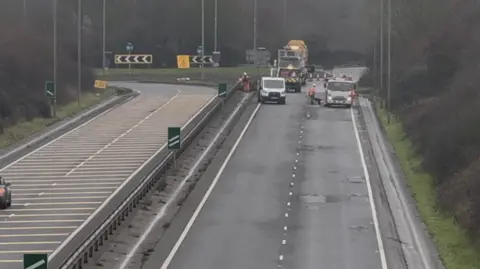Jamie Morris Work being carried out to repair potholes on a dual carriageway. One side of the road is closed as workmen carry out the repairs.