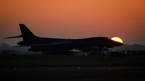 Leon Neal/Getty Images A Rockwell B-1 Lancer heavy bomber sits on the tarmac as the sun rises above RAF Fairford