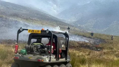 Fire vehicle and firefighters tackle fire at Tintwistle Moor
