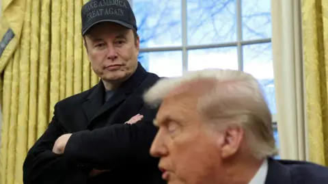 Elon Musk listens to U.S. President Donald Trump speak in the Oval Office of the White House in Washingto