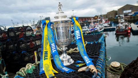 The Scottish Cup perched on the edge of a harbour