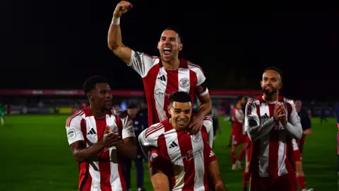 Brackley Town players celebrate beating Notts County in the FA Cup third round